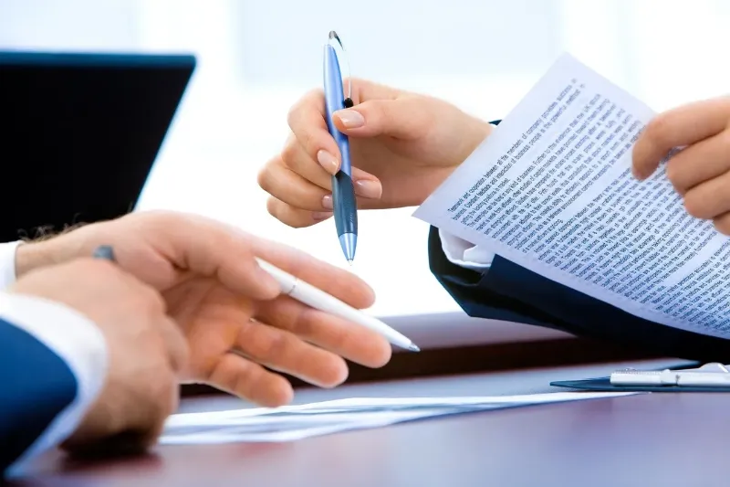 2 people with pens in their hands looking over a contract