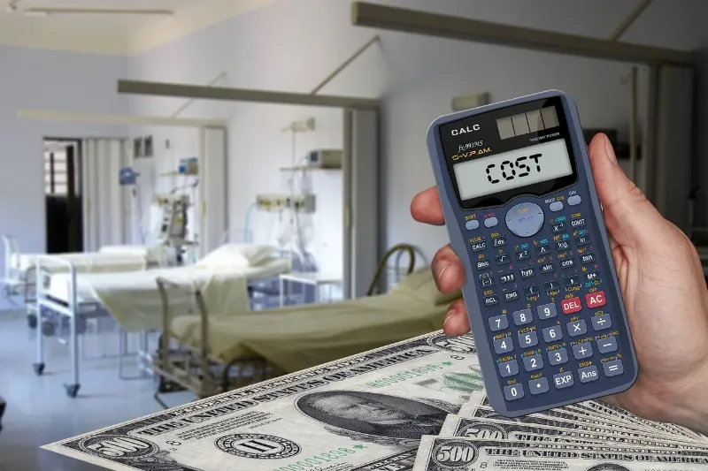 person holding a calculator in hospital with cash around his hand