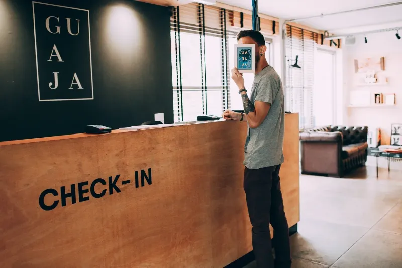 man hiding behind a brochure at a check-in booth