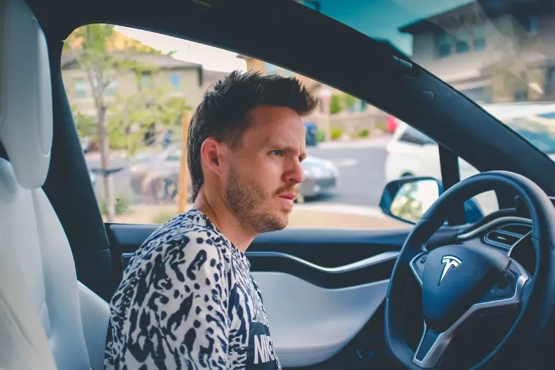 confused man behind the wheel of his Tesla